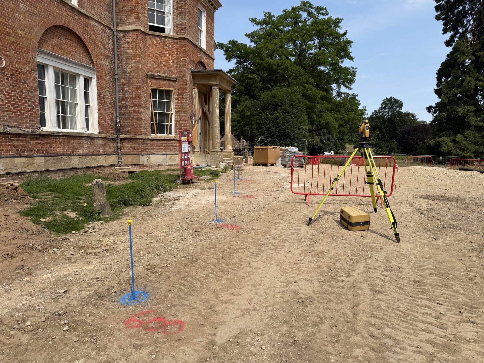 Total station set up in front of a Georgian country house with setting-out pins in the ground