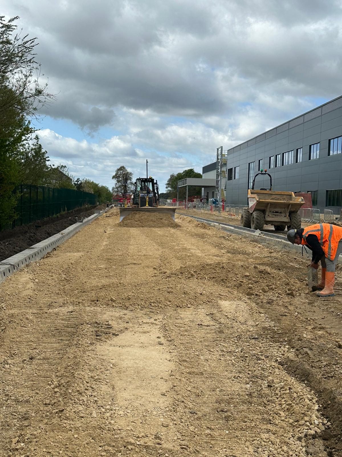 Dozer spreading stone sub-base between new kerb lines beside an industrial unit
